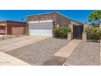 Charming home featuring stone accents, a two-car garage, and a welcoming gated entrance at 902 E Wahalla Ln, Phoenix, AZ 85024