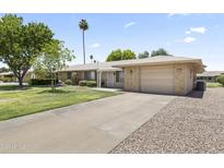 Charming single-level home with a well-maintained lawn and a spacious driveway leading to the garage at 9434 W Greenway Rd, Sun City, AZ 85351