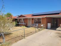 Ranch-style home with a red roof, solar panels, a covered parking area, and a chain link fence at 1116 E Almeria Rd, Phoenix, AZ 85006