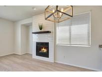 Bright living room featuring a tile fireplace, modern light fixture, and window with horizontal blinds at 18371 W Capistrano Ave, Goodyear, AZ 85338