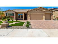 Charming single-story home with a well-manicured front yard and brick-paved driveway leading to a two-car garage at 18908 W Montebello Ave, Litchfield Park, AZ 85340