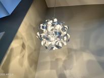 Modern, artistic chandelier with ribbon-like accents hanging from the ceiling of home at 3810 N 106Th Dr, Avondale, AZ 85392