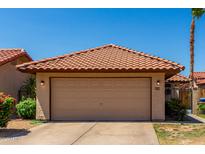 Charming home featuring a two-car garage with a tile roof, set against a clear blue sky at 5216 E Half Moon Dr, Phoenix, AZ 85044