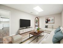 Bright living room features a skylight, modern furnishings, and an arched doorway to the next room at 6223 W Earll Dr, Phoenix, AZ 85033