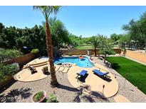 Inviting backyard pool with lounge chairs, manicured lawn, mature landscaping, and clear blue skies at 6937 W Jackrabbit Ln, Peoria, AZ 85383