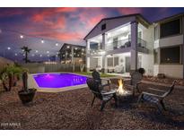 Inviting backyard features a sparkling pool, fire pit with chairs, and a charming two-story home with balconies at 20139 N Bustos Way, Maricopa, AZ 85138