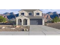 Inviting two-story home featuring a gray garage door, desert landscaping, and mountain views at 24237 W Southgate Ave, Buckeye, AZ 85326