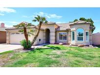 Charming single-story home with tile roof, arched entryway, and lush green lawn with well maintained landscaping at 705 W Country Estates Ave, Gilbert, AZ 85233