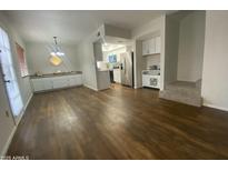 Open-concept living room and kitchen with stainless steel appliances and modern white cabinetry at 10828 N Biltmore Dr # 133, Phoenix, AZ 85029