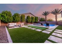 Spacious backyard with pool, patio seating, putting green, and artificial turf at 14481 W Via Del Oro --, Surprise, AZ 85379