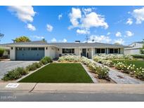 Charming home with a well-manicured front yard, complete with lush green grass and beautiful white flowers at 4010 E Coolidge St, Phoenix, AZ 85018