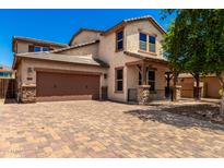Two-story home featuring stucco siding, a covered porch, paver driveway, and a two-car garage at 4277 N 180Th Ln, Goodyear, AZ 85395