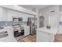 Bright kitchen features stainless steel appliances, white cabinetry and countertops, with a colorful backsplash at 44853 W Jack Rabbit Trl, Maricopa, AZ 85139