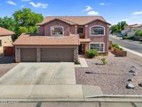 Two-story home showcasing a three-car garage and desert-style landscaping, perfect for curb appeal at 941 E Stirrup Ln, San Tan Valley, AZ 85143