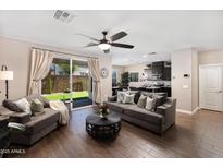 Open living room features hardwood floors, ceiling fan and a sliding glass door with access to the backyard at 1255 N Arizona Ave # 1013, Chandler, AZ 85225
