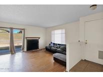 Bright living room with hardwood floors, fireplace, and sliding glass door to patio at 12842 S Wakial Loop, Phoenix, AZ 85044