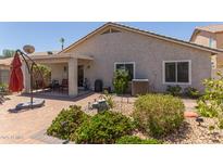 An outdoor patio includes brick pavers, an umbrella, and comfortable seating for relaxing and entertaining at 1628 E Aspen Ave, Buckeye, AZ 85326