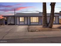 Charming single-story home with a white exterior and blue trim and a large palm tree in the front yard at 2207 W Bentrup St, Chandler, AZ 85224