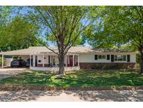 Charming home with a well-manicured lawn, mature tree, and inviting red front door at 4238 E Mitchell Dr, Phoenix, AZ 85018