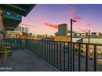 Balcony view showcases urban landscape with outdoor seating, metal railings, and buildings against a vivid sky at 424 S 2Nd St # 203, Phoenix, AZ 85004