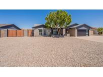 Charming single-story home with xeriscaped yard, complemented by mature tree and modern garage door at 6719 S Hardy Dr, Tempe, AZ 85283