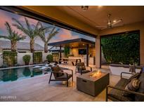 Inviting backyard featuring a sparkling pool, outdoor kitchen, fire pit, and comfortable seating area, perfect for entertaining at 9255 W Los Gatos Dr, Peoria, AZ 85383