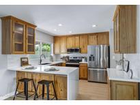 Well-lit kitchen featuring wood cabinetry, stainless steel appliances, and a breakfast bar with white countertops at 1119 W Ellis Dr, Tempe, AZ 85282