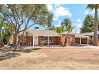 Charming single-story red brick home with a well-maintained yard and mature trees in a sunny neighborhood at 1238 E Cambridge Ave, Phoenix, AZ 85006