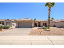 Charming single-story home featuring a desert landscape, two-car garage, and a beautiful palm tree on a sunny day at 16354 W Labyrinth Ln, Surprise, AZ 85374