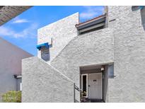 View of the building's facade featuring a stucco exterior, stairs, and a gated entrance at 220 N 22Nd Pl # 2036, Mesa, AZ 85213