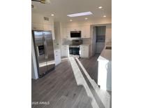 Bright kitchen featuring stainless steel appliances, white cabinets, tiled backsplash, and wood-look tile flooring at 10025 W Shasta W Dr, Sun City, AZ 85351