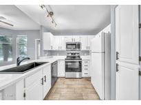 Updated kitchen features white cabinets, quartz countertops, stainless steel appliances and wood-look tile flooring at 11375 E Sahuaro Dr # 1008, Scottsdale, AZ 85259
