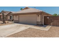 Charming single-story home with a two-car garage, desert landscaping, and a tile roof at 16333 W Paradise Ln, Surprise, AZ 85388