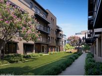 Modern condos with balconies overlook a manicured green lawn and walkway lined with blooming flowers and lush greenery at 19360 N 73Rd St # 1069, Scottsdale, AZ 85255