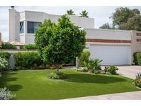 Charming home showcasing well-manicured landscaping, a pristine lawn, and an attached two-car garage at 8068 E Del Trigo Rd, Scottsdale, AZ 85258