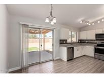Bright kitchen with white cabinets, stainless steel appliances, and wood-look flooring with sliding door access to back yard at 19802 N 3Rd Ave, Phoenix, AZ 85027