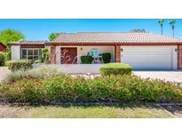 Well-maintained home featuring desert landscaping with green grass, red flowers and a red tile roof at 333 E Caribbean Ln, Phoenix, AZ 85022