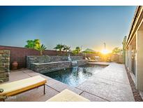 A tranquil pool area with waterfall feature, lounge chairs and lush landscaping creates an inviting backyard retreat at 3597 W Mineral Butte Dr, San Tan Valley, AZ 85144