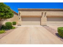 View of the garages and driveways of a row of houses with low shrubs under a clear blue sky at 6730 E Hermosa Vista Dr # 72, Mesa, AZ 85215