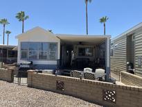 Charming mobile home with a cozy covered patio and well-maintained landscaping with palm trees at 2290 S Seminole Dr, Apache Junction, AZ 85119