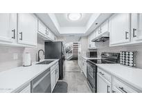 Galley kitchen with white cabinets, quartz countertops, black appliances and subway tile backsplash at 2615 N Hayden Rd # 114, Scottsdale, AZ 85257