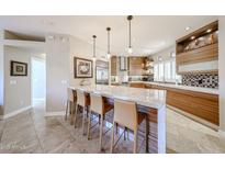 Modern kitchen with stainless steel appliances, marble countertops, and stylish pendant lighting over the breakfast bar at 8880 E Paraiso Dr # 120, Scottsdale, AZ 85255