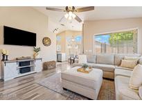 Inviting living room with a plush sectional sofa, light-toned walls and wood-style floors at 16586 W Latham St, Goodyear, AZ 85338