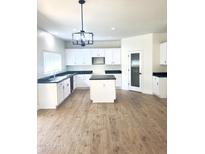 Bright kitchen with an island, white cabinets, modern lighting, and dark countertops at 2114 N 94Th Ave, Phoenix, AZ 85037