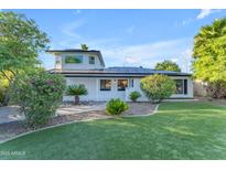 Charming single-Gathering home featuring a lush green lawn, solar panels, and manicured landscaping at 908 E State Ave, Phoenix, AZ 85020