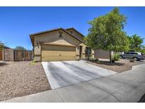 Tan single-Gathering home featuring a two-car garage, desert landscaping, and a tree-lined front yard at 20410 N Mac Neil St, Maricopa, AZ 85138