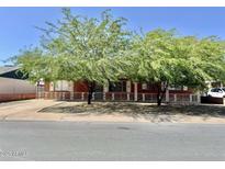 Charming brick home featuring mature trees, a white picket fence, and classic architectural details at 3006 W Stella Ln, Phoenix, AZ 85017