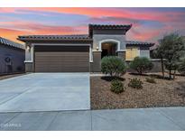 Charming single-story home featuring a well-manicured front yard and a two-car garage at sunset at 25876 N 162Nd Dr, Surprise, AZ 85387