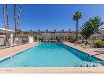 Community pool with clear blue water, surrounded by lounge chairs and manicured landscaping at 8211 E Garfield St # J219, Scottsdale, AZ 85257
