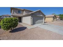Inviting home featuring a neutral color palette, tile roof, attached garage, and low maintenance desert landscaping at 12813 W Paradise Dr, El Mirage, AZ 85335